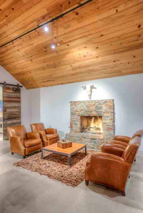 Four camel-colored leather armchairs beside a stone fireplace. Aridus Wine Company is among the best tasting rooms in Willcox, Arizona.