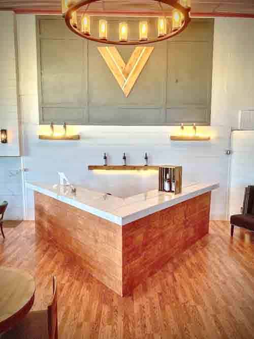 A circular chandelier hangs above a V-shaped bar countertop. It's the Strive Vineyards tasting room in downtown Willcox, Arizona.